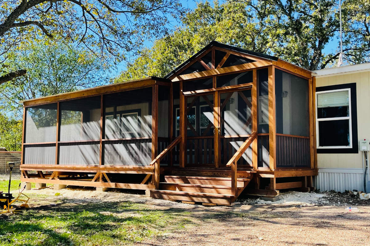 Large screened-in portable deck with gabled entrance and stairs