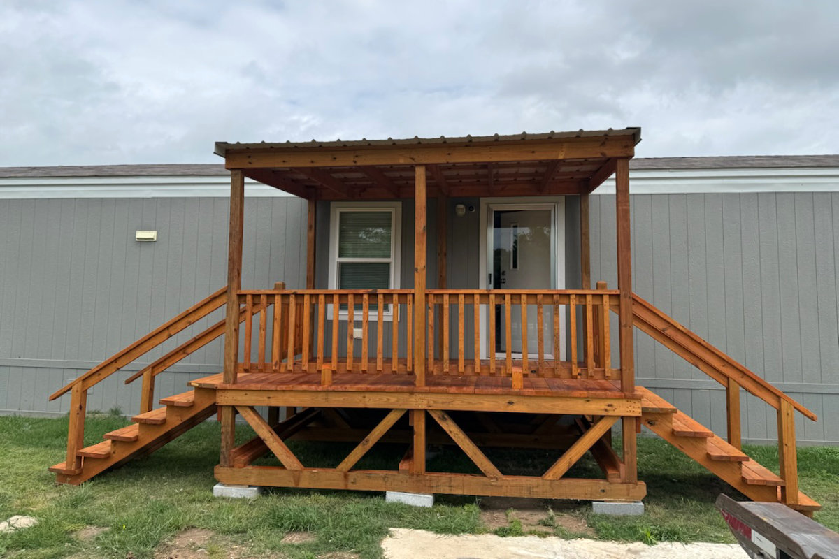 Covered brown-stained portable deck with metal roof and two stairs