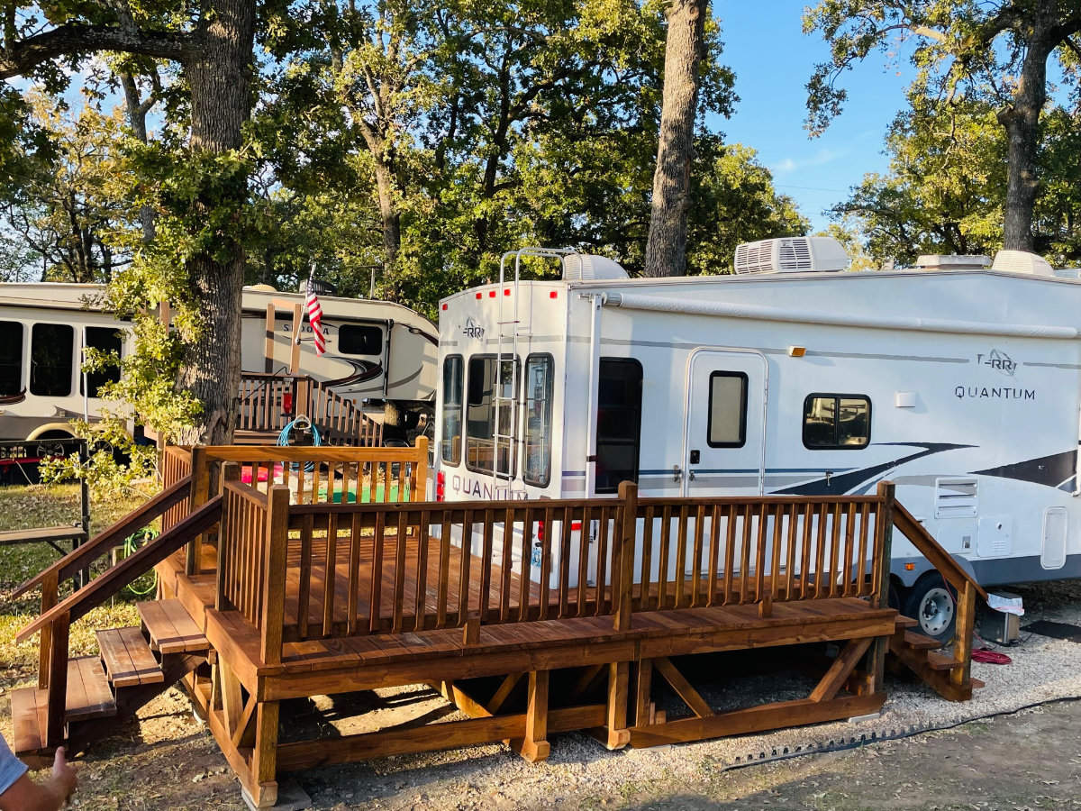 Large dark portable deck with railings in front of an RV