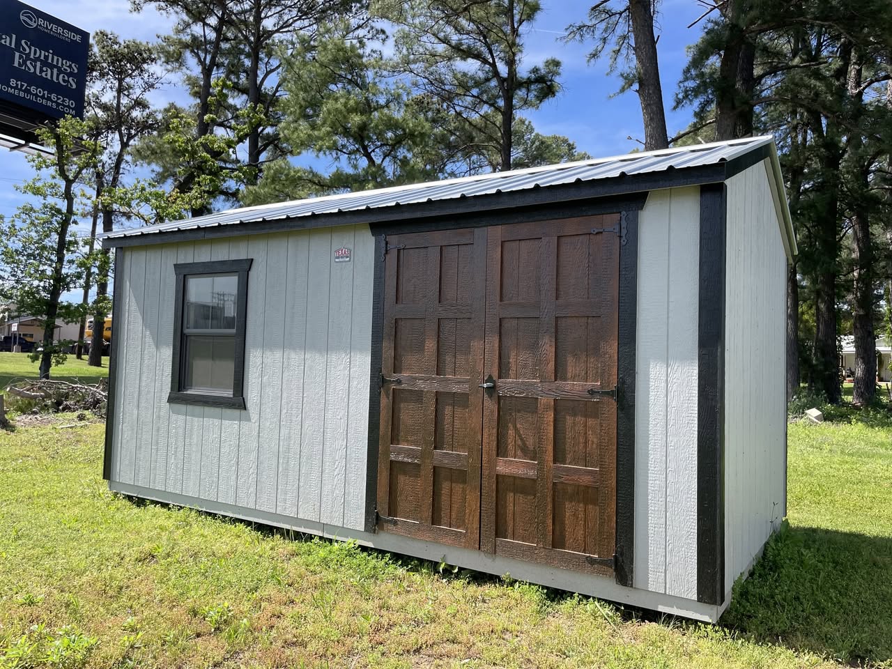 White barn-style storage shed with brown double doors